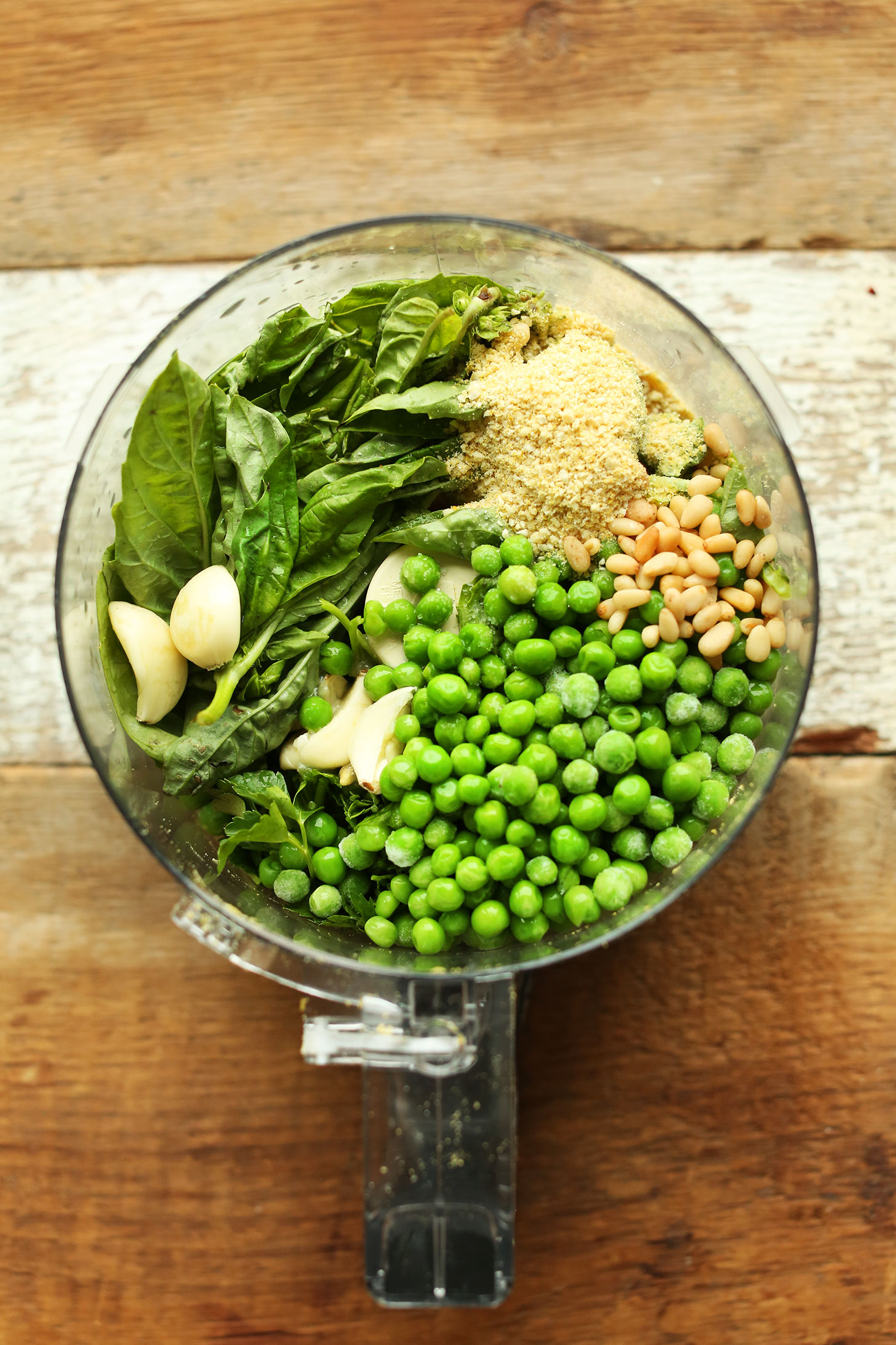 Food processor with ingredients for making our homemade vegan Pea Pesto recipe