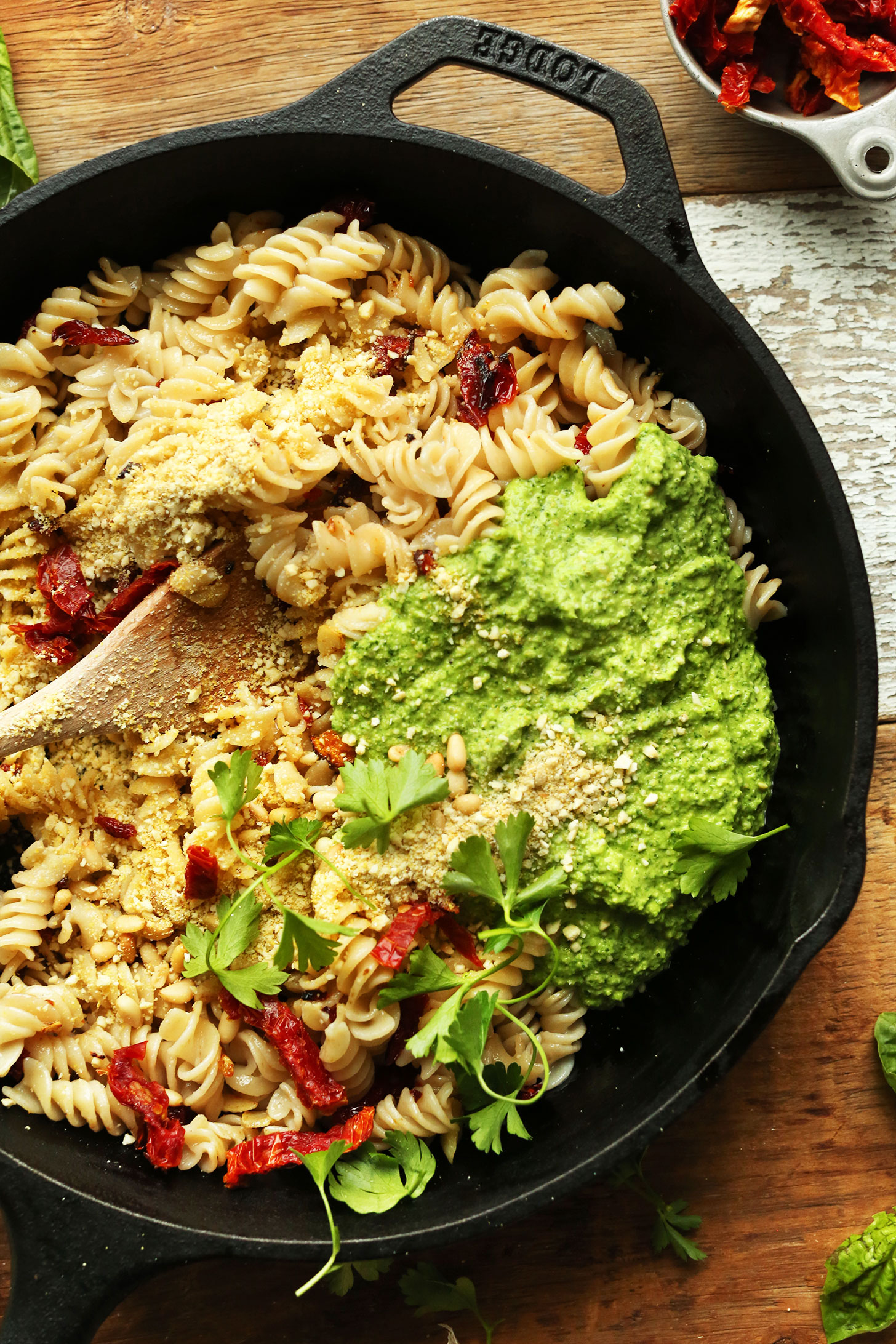 Cast-iron skillet with gluten-free noodles, sun-dried tomatoes, and pea pesto