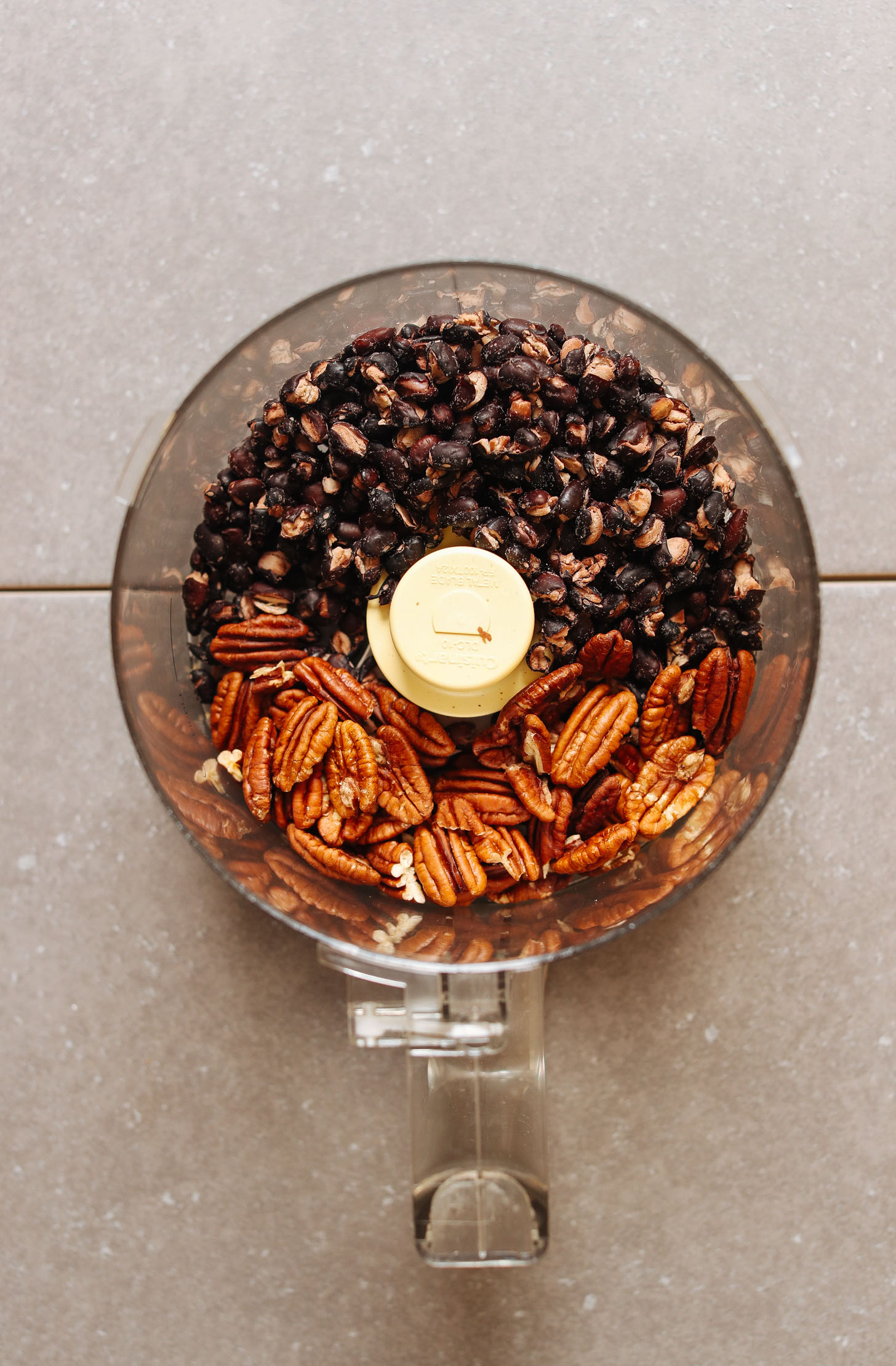Black beans and pecans in the food processor ready to be pulsed for BBQ Black Bean Burgers