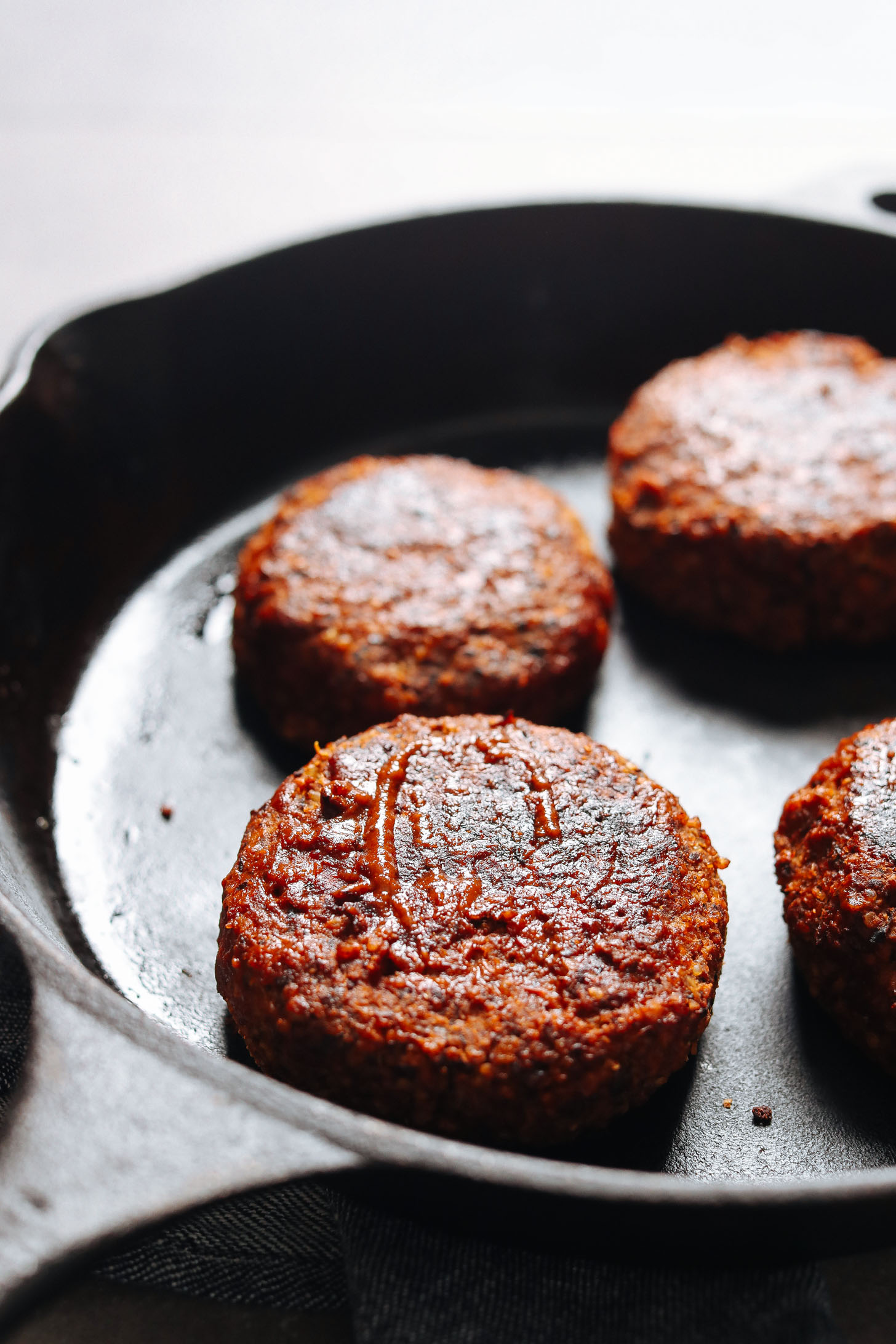 Gluten-free and vegan BBQ Black Bean Burger patties cooking in a skillet