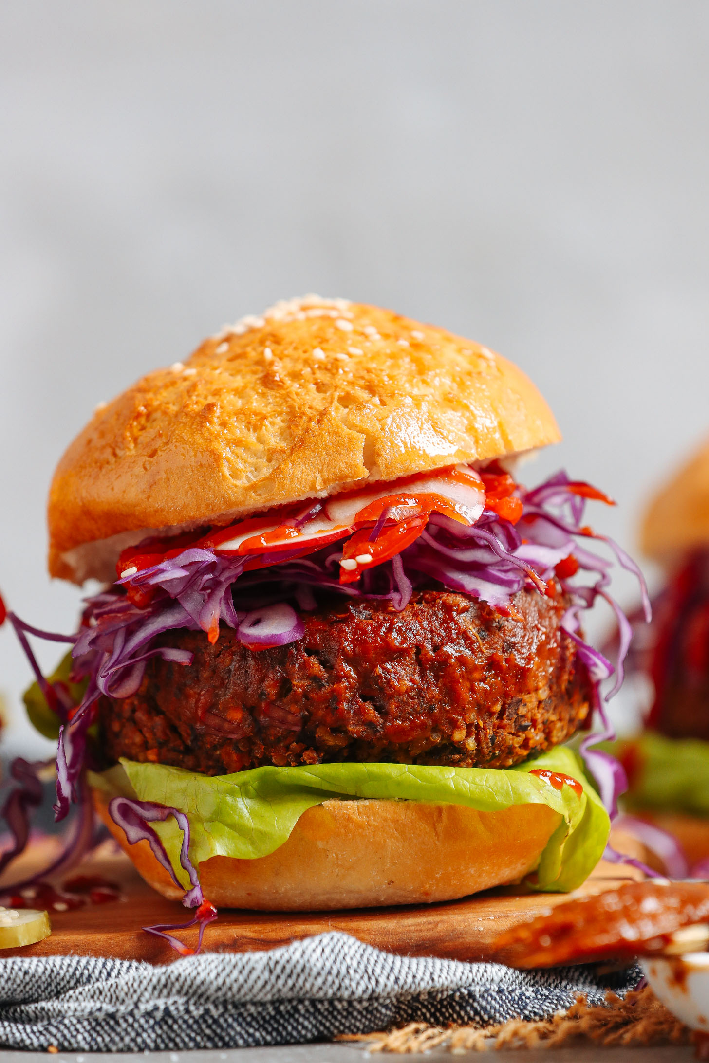 Close up shot of a BBQ Black Bean Burger on a bun with fresh vegetables