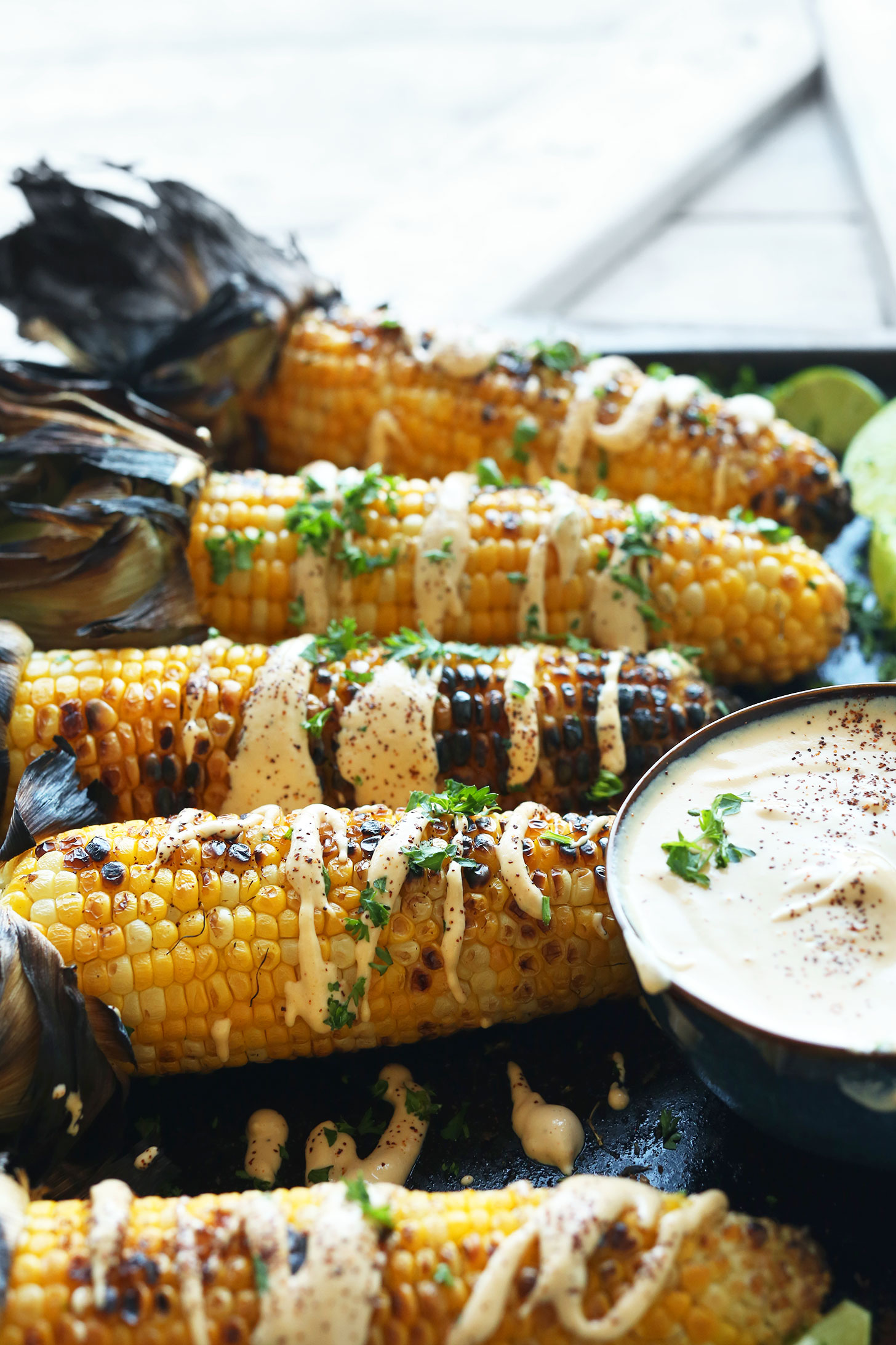 Cobs of Mexican Grilled Corn with a bowl of gluten-free vegan Sriracha Aioli