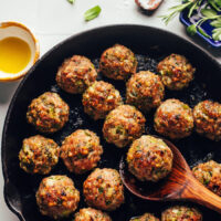 Spoon resting in a cast iron skillet of Thanksgiving turkey meatballs