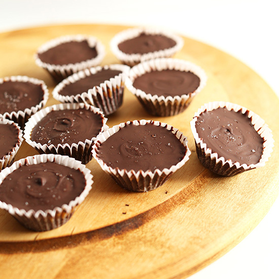 Wood cutting board filled with a batch of our homemade Caramel Almond Butter Cups