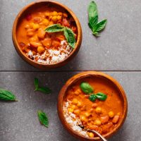 Two bowls of rice beside our Creamy Chickpea Tomato Peanut Stew recipe