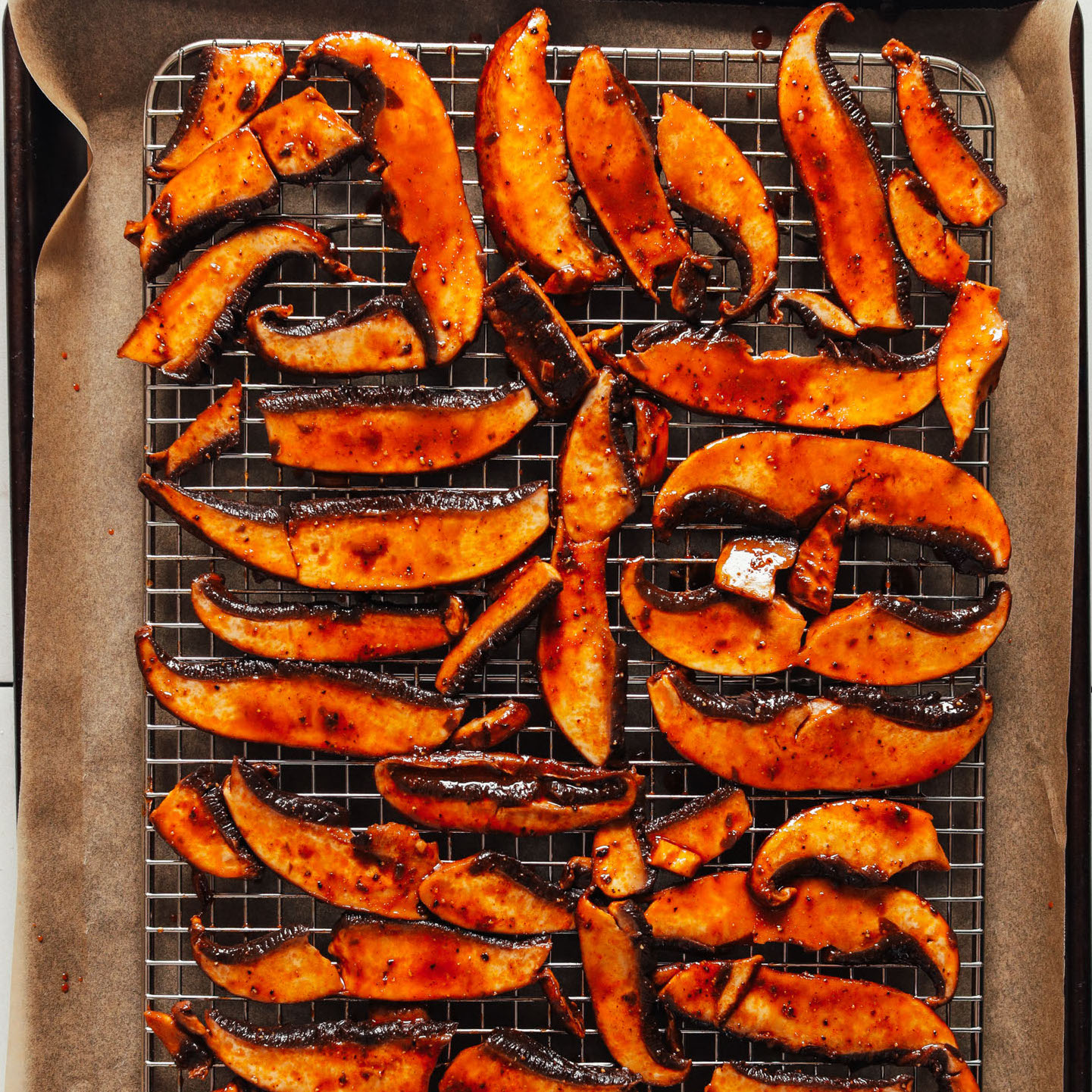Crispy vegan Portobello Bacon on a wire rack over a parchment-lined baking sheet