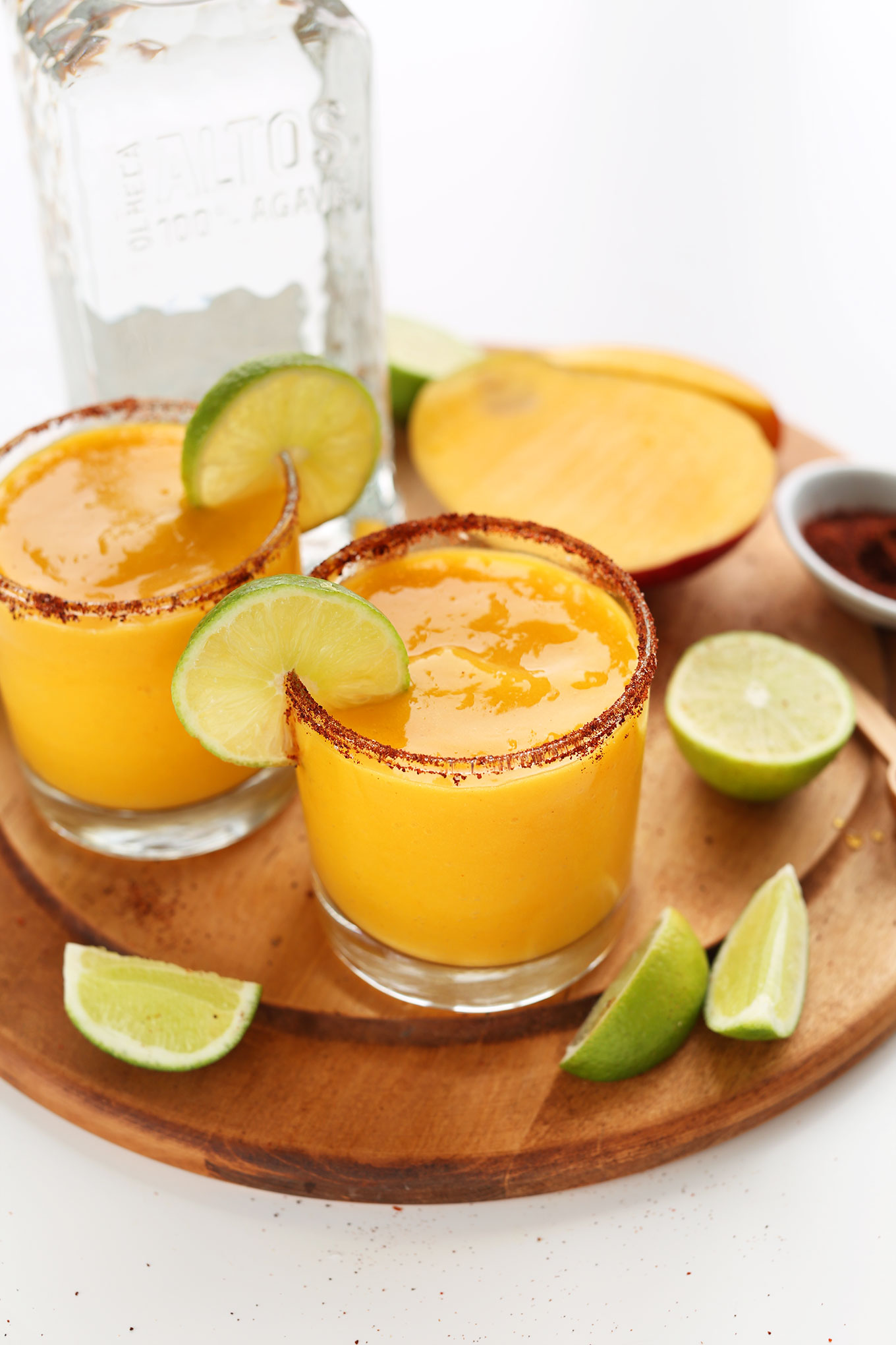 Perfectly sweet, tart, and spicy Blended Mango Chili Margaritas on a cutting board with fresh limes