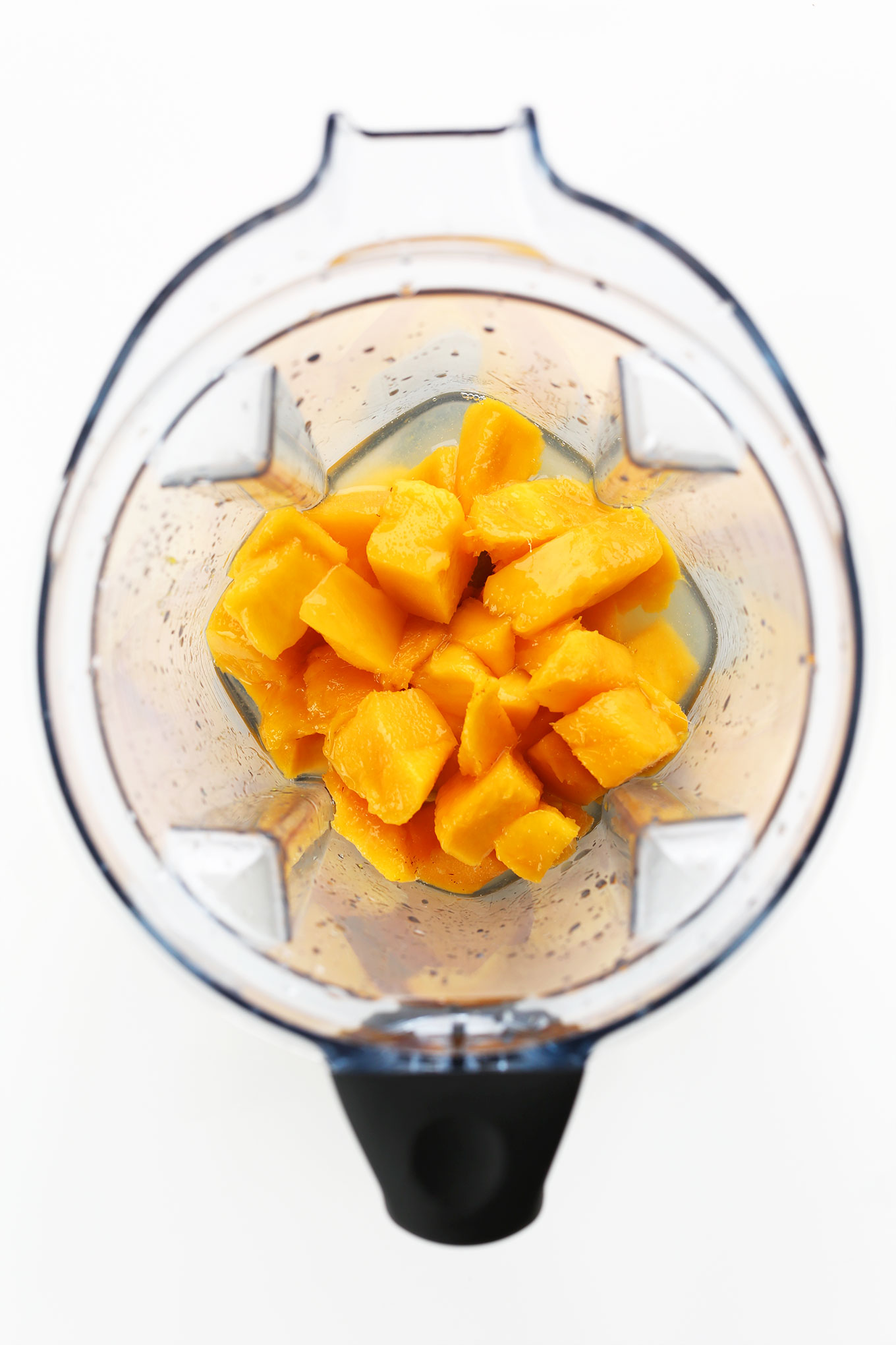 Blender filled with ingredients for making easy blended mango margaritas