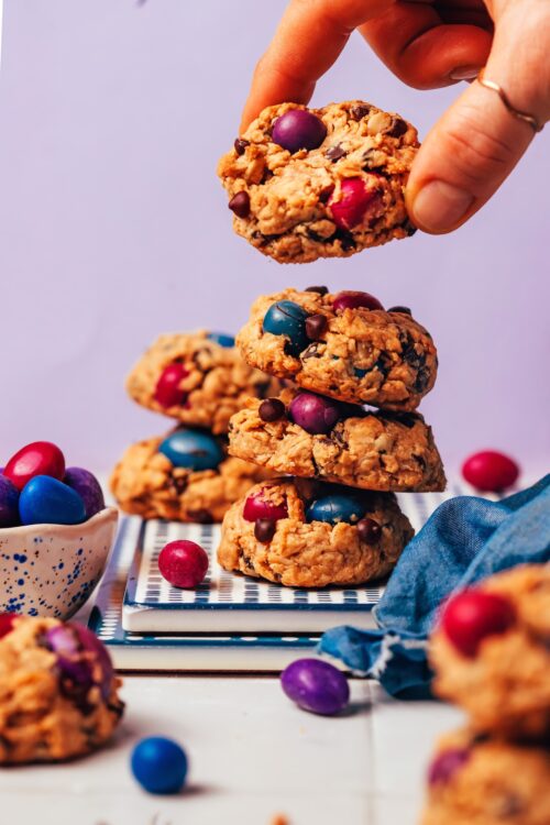 Holding a gluten-free monster cookie above a stack of more cookies