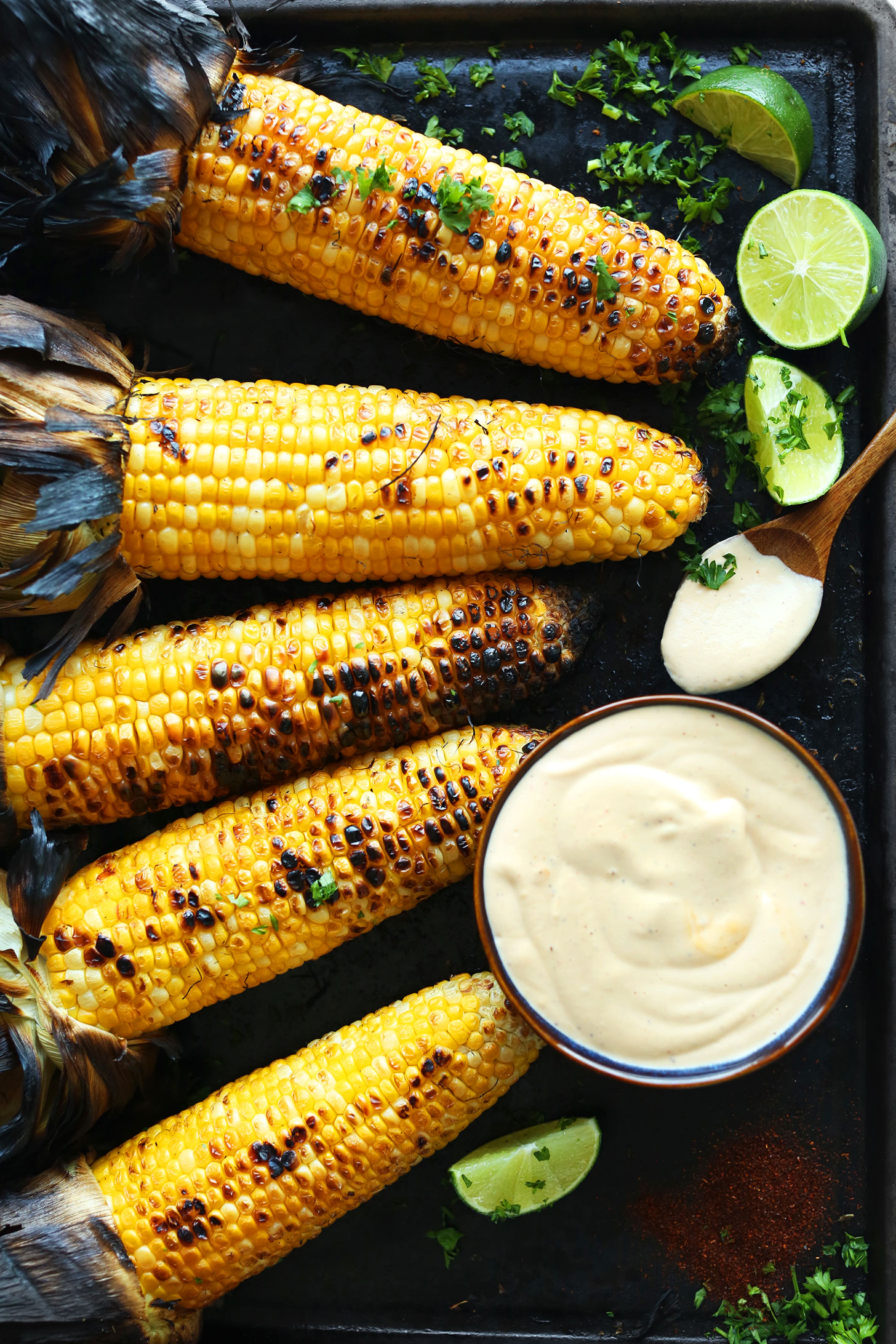 Baking sheet with grilled corn on the cob and sriracha aioli for a perfect summer BBQ dish