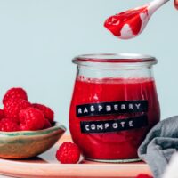 Holding a spoonful of raspberry compote over a jar of more compote