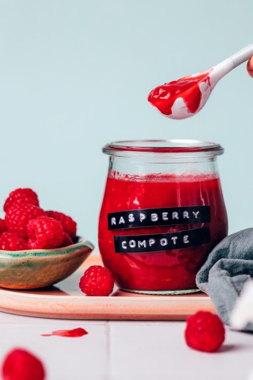 Holding a spoonful of raspberry compote over a jar of more compote