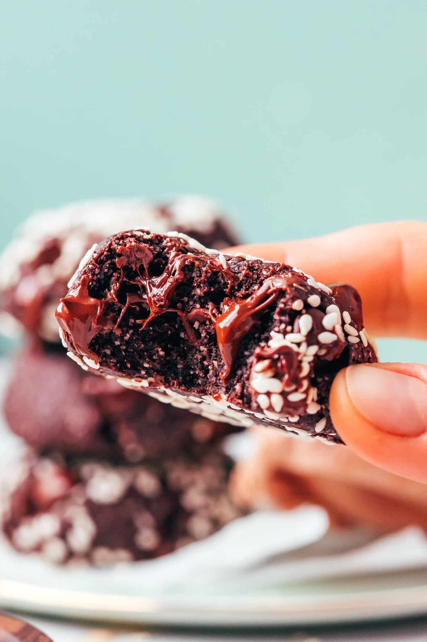 Close up photo of a partially eaten chocolate tahini cookie with melty chocolate chips in it