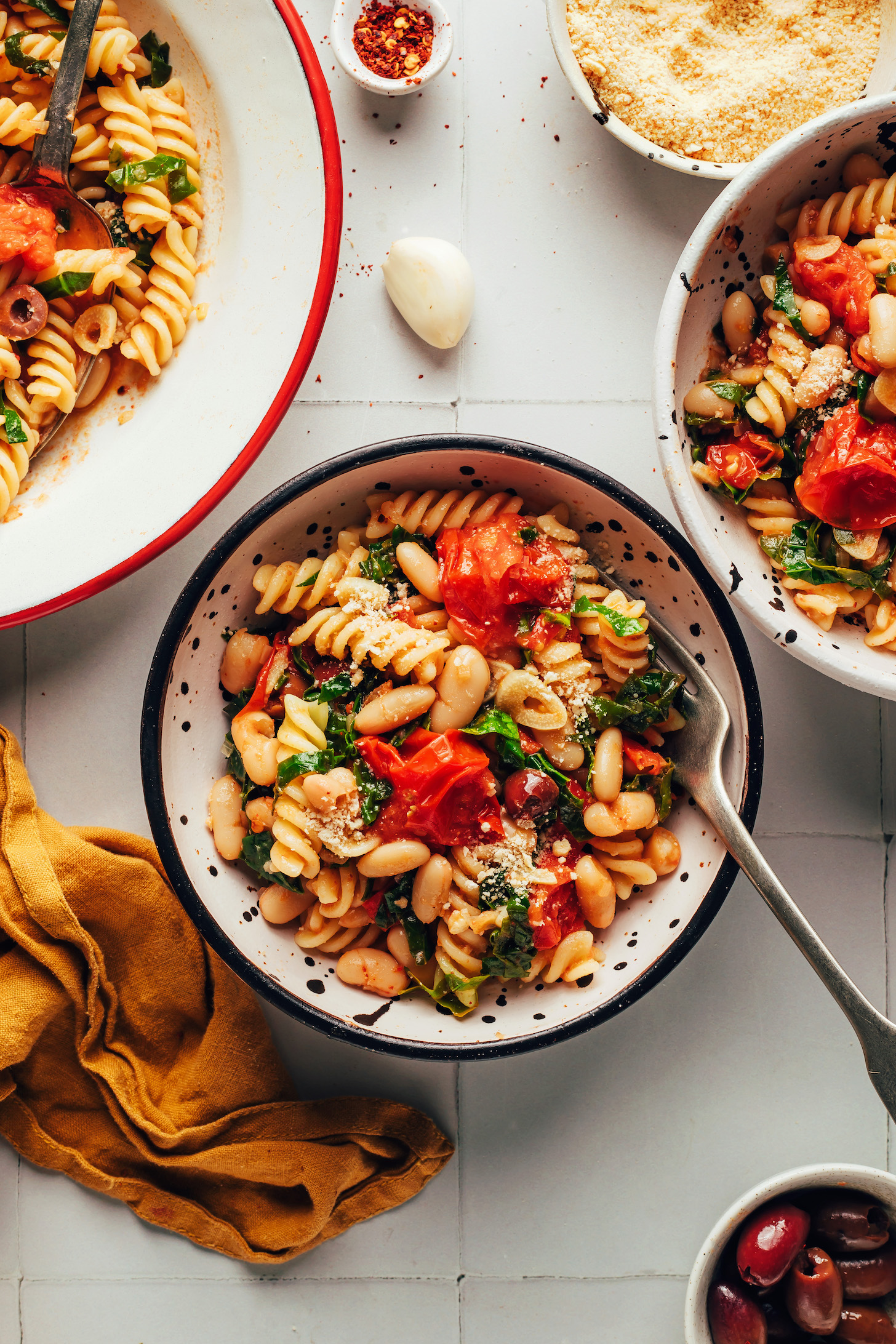 Overhead shot of bowls of garlicky cherry tomato pasta with white beans
