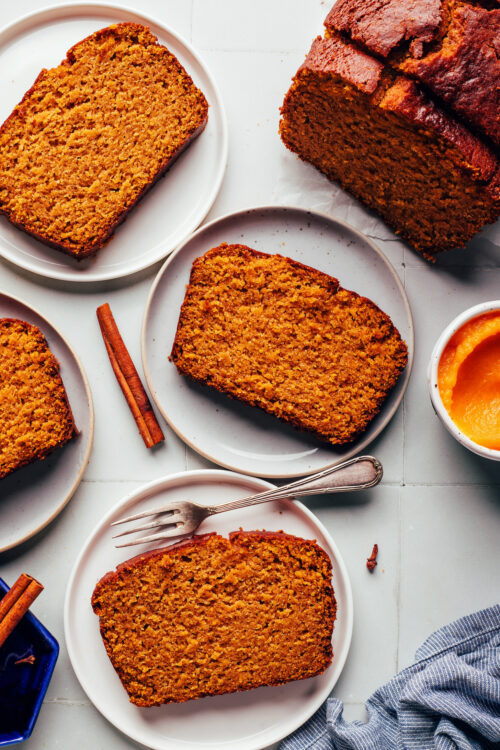 Slices of our gluten-free pumpkin bread on plates next to a half loaf