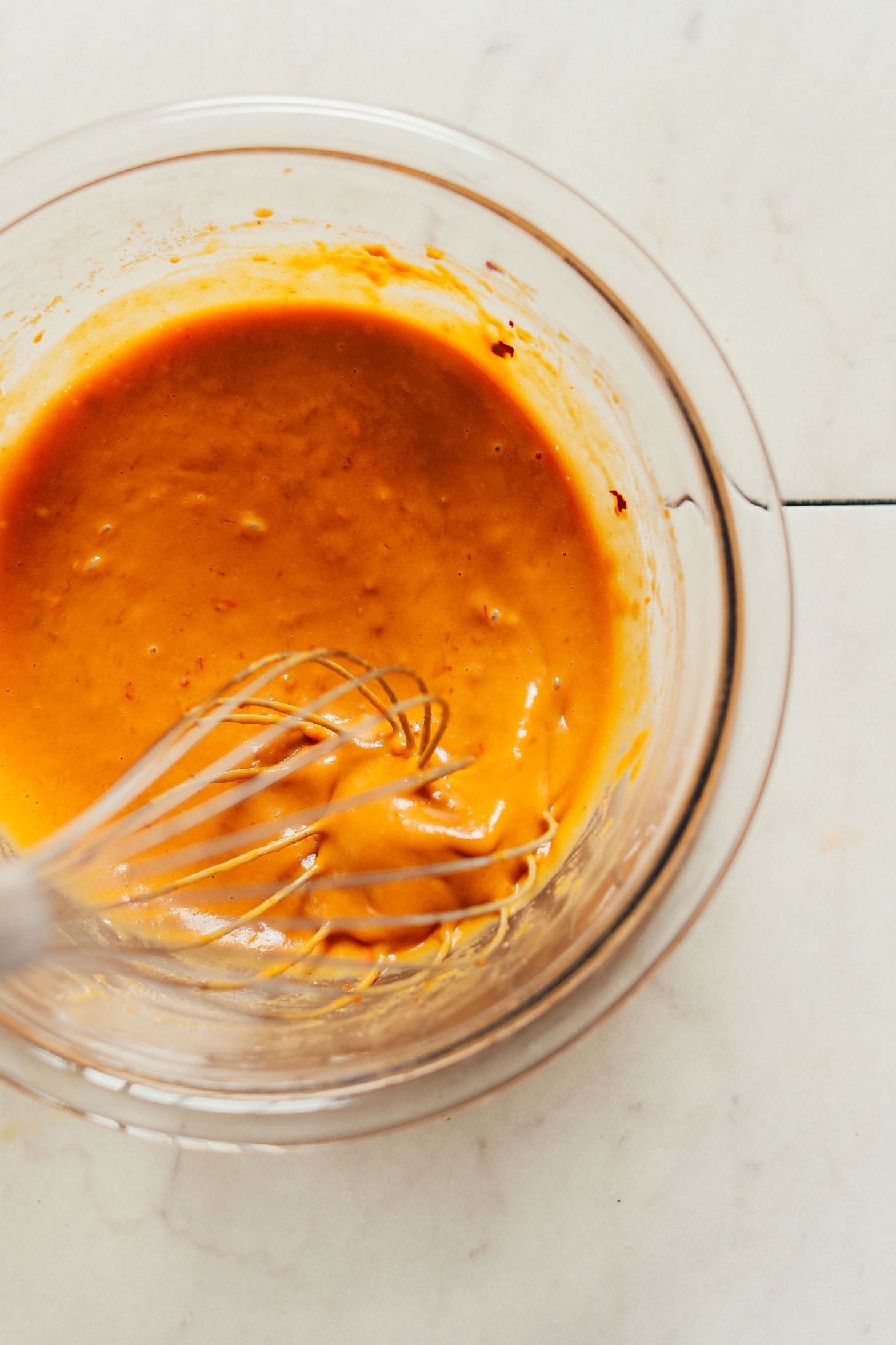 Whisking gluten-free vegan Peanut Dressing ingredients in a glass bowl
