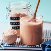 Stirring our Instant Chai Latte Mix in a glass with hot water and sweetener