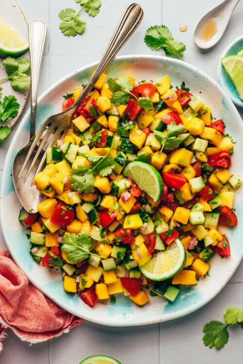 Overhead photo of a bowl of our Easy Mango Cucumber Salad topped with two lime wedges