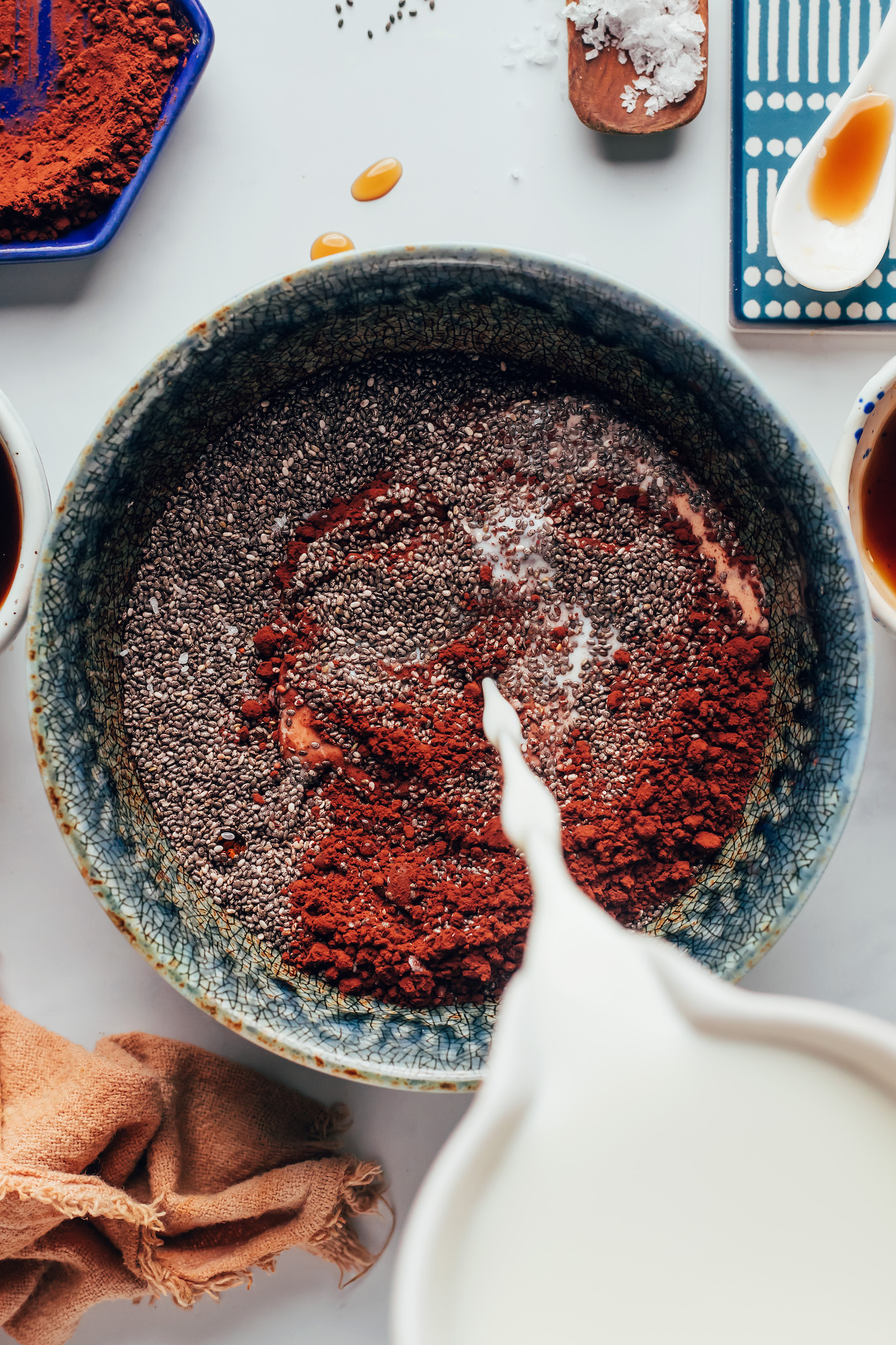 Pouring dairy-free milk into a bowl of chia seeds and cocoa powder
