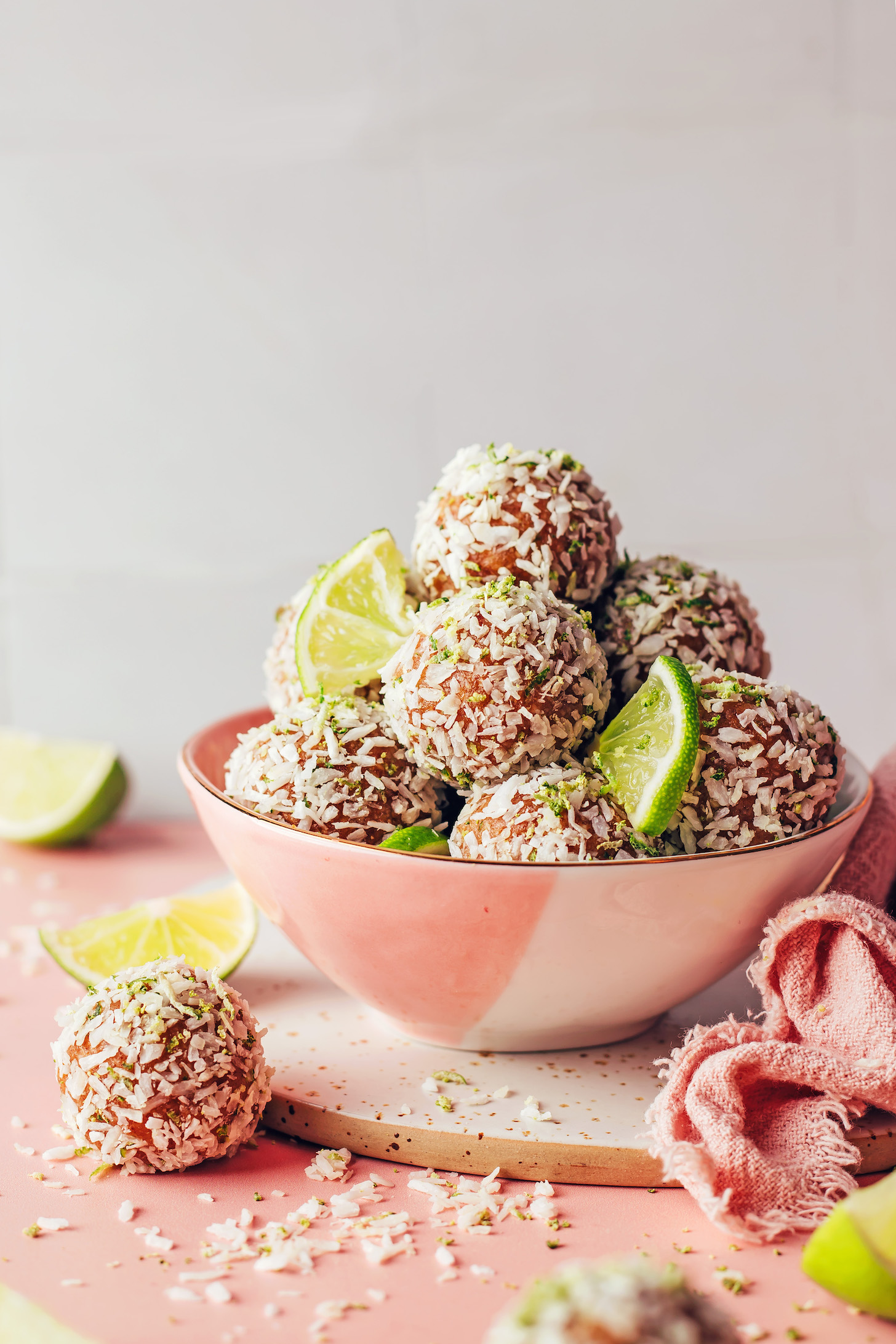 Bowl of no-bake coconut lime energy bites and lime slices