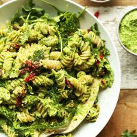 Big bowl of Gluten-Free Vegan Pea Pesto Pasta made with sun-dried tomatoes and arugula
