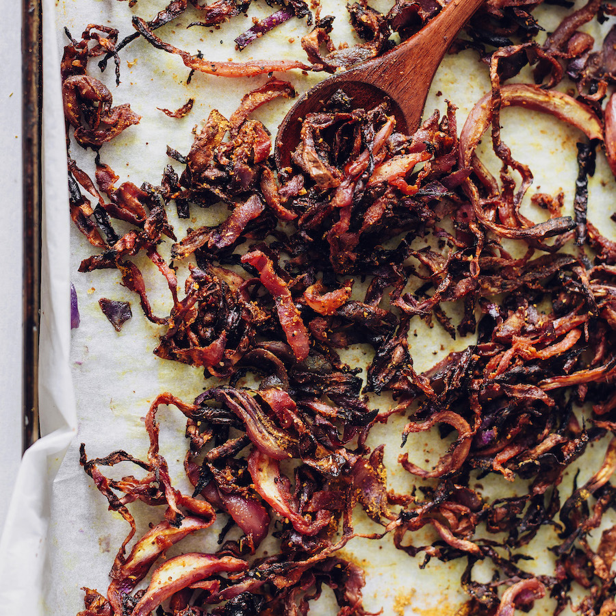Wooden spoon scooping up roasted cabbage on a baking sheet