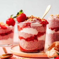 Jars of strawberry chia pudding layered with dairy-free yogurt, strawberry compote, and crushed graham crackers