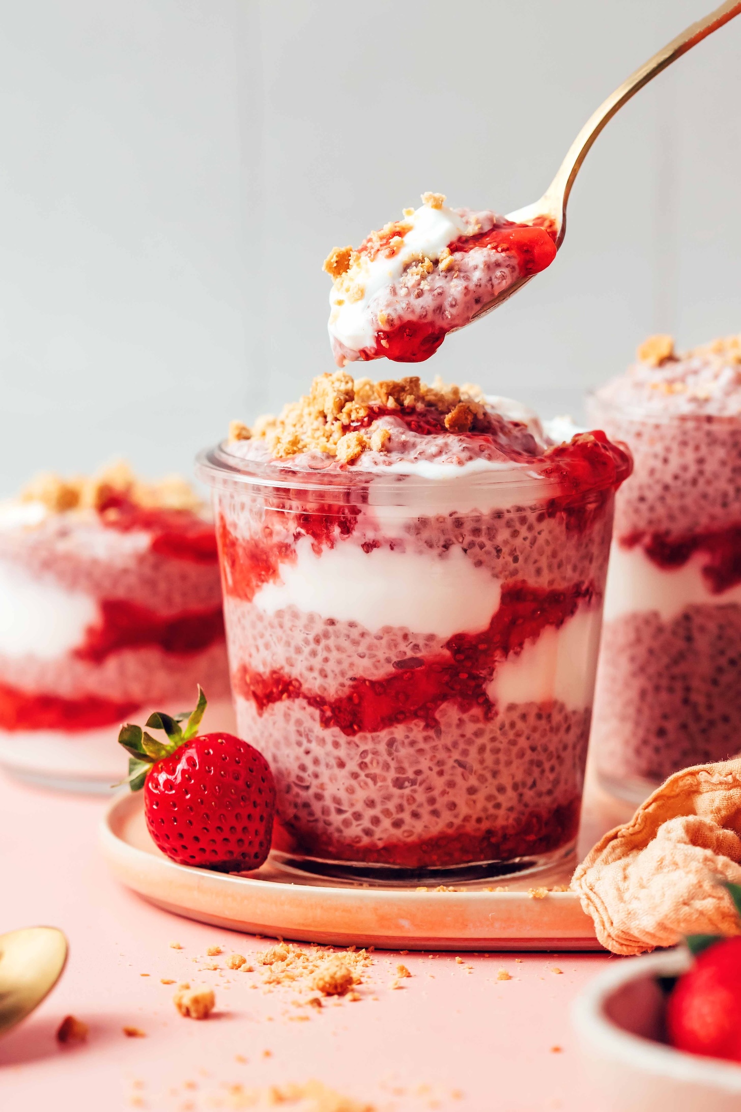 Spoon holding a bit of strawberry chia pudding above a jar