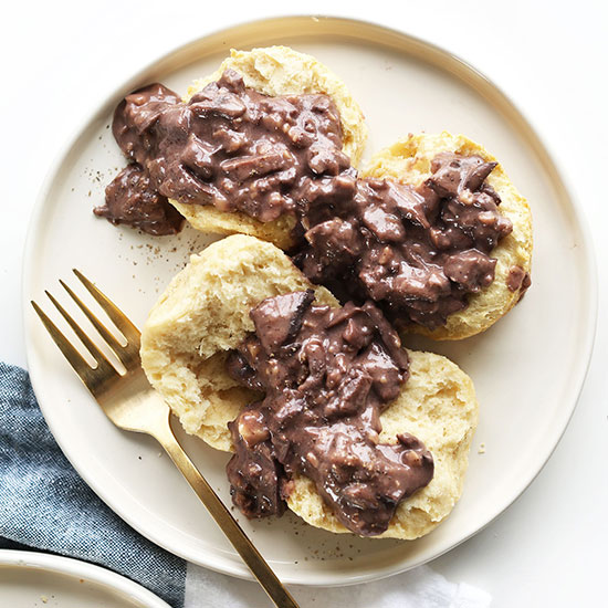 Large plate with two Vegan biscuits sliced open and topped with gravy
