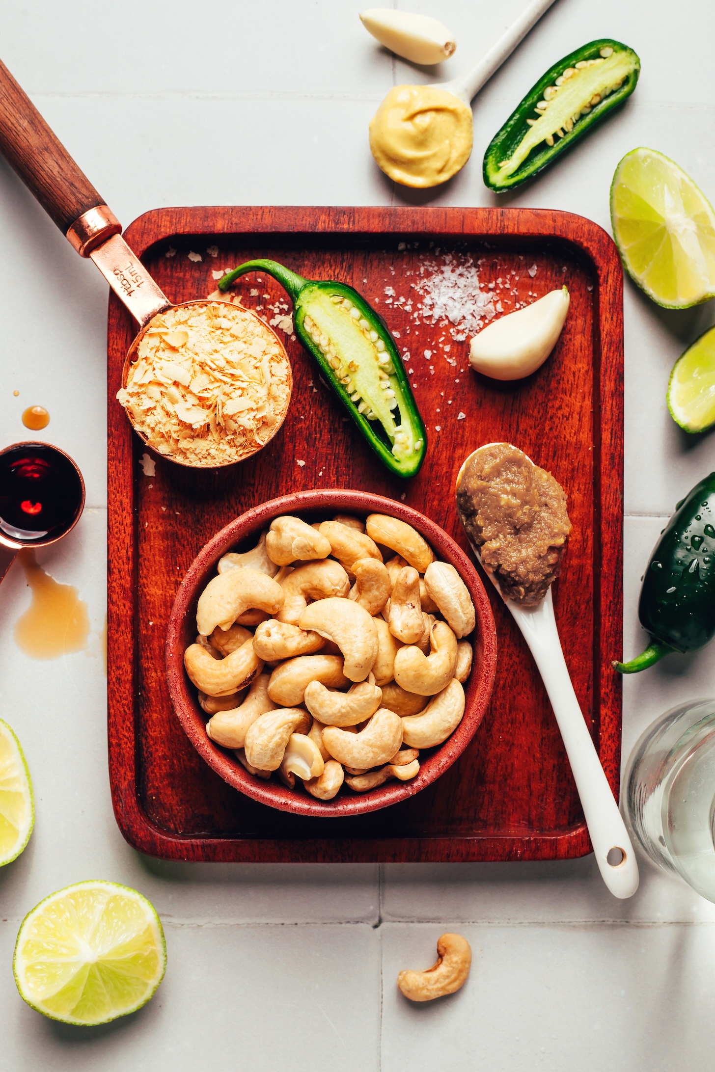 Wood board with cashews, miso paste, garlic, jalapeños, limes, mustard, salt, and maple syrup