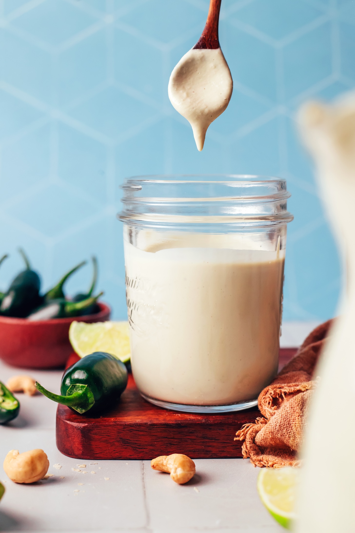 Cashew dressing dripping off a spoon into a glass jar