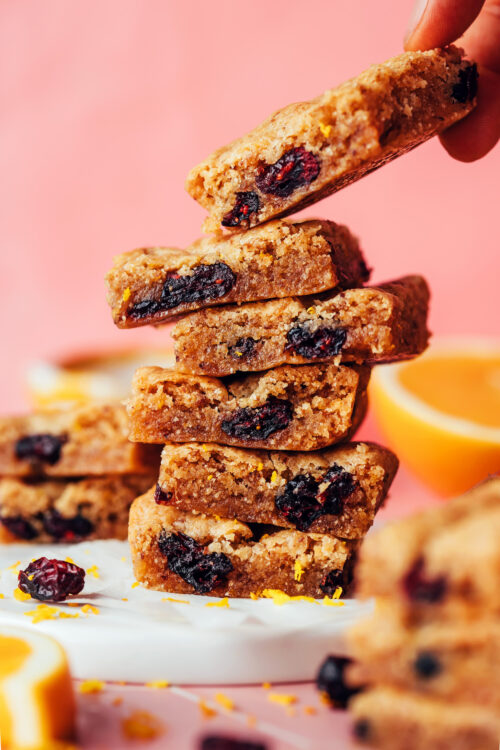 Picking up a cranberry orange cookie bar from a stack of cookie bars