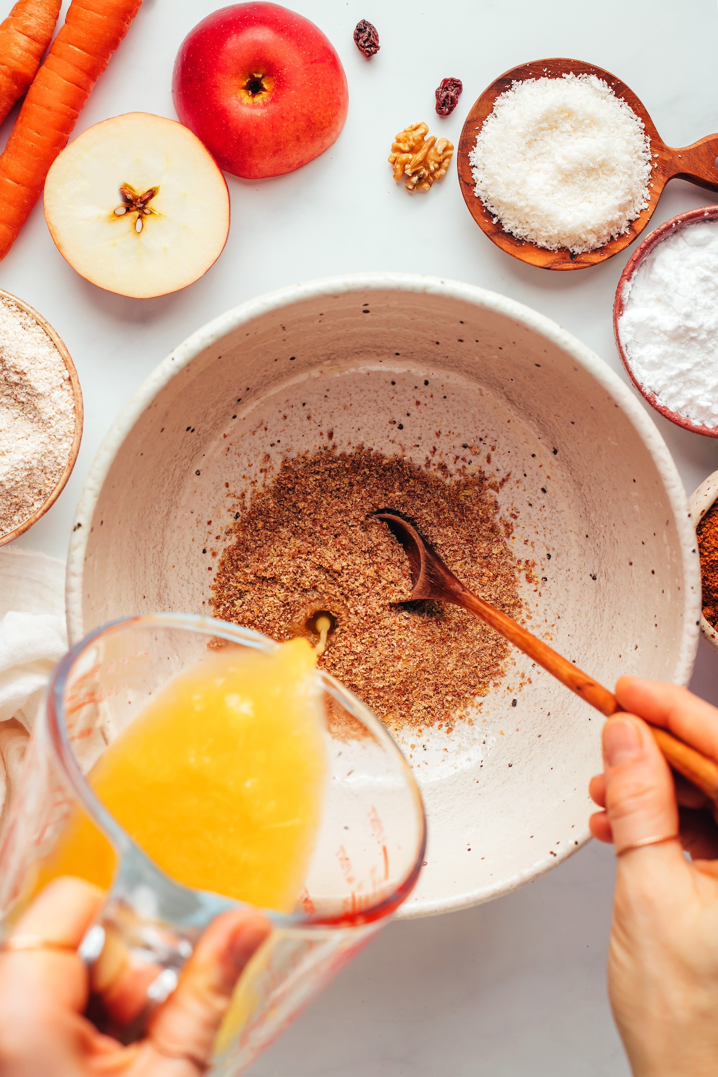 Pouring orange juice into a bowl of flaxseed meal